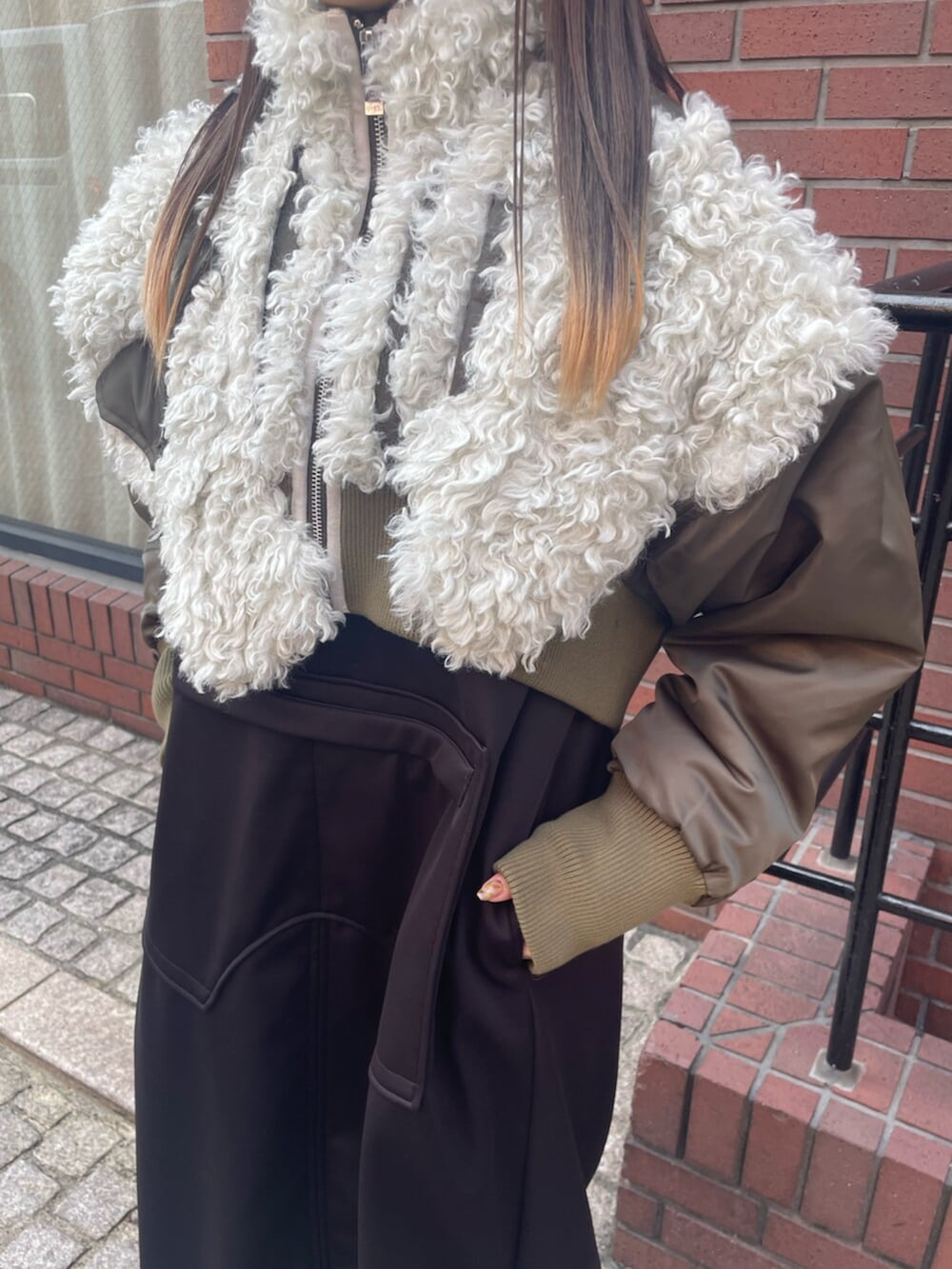 グリーン系のブルゾン、ブラック系のワンピース、ブラック系のブーツを着用したレディースの冬コーディネートの3枚目の写真