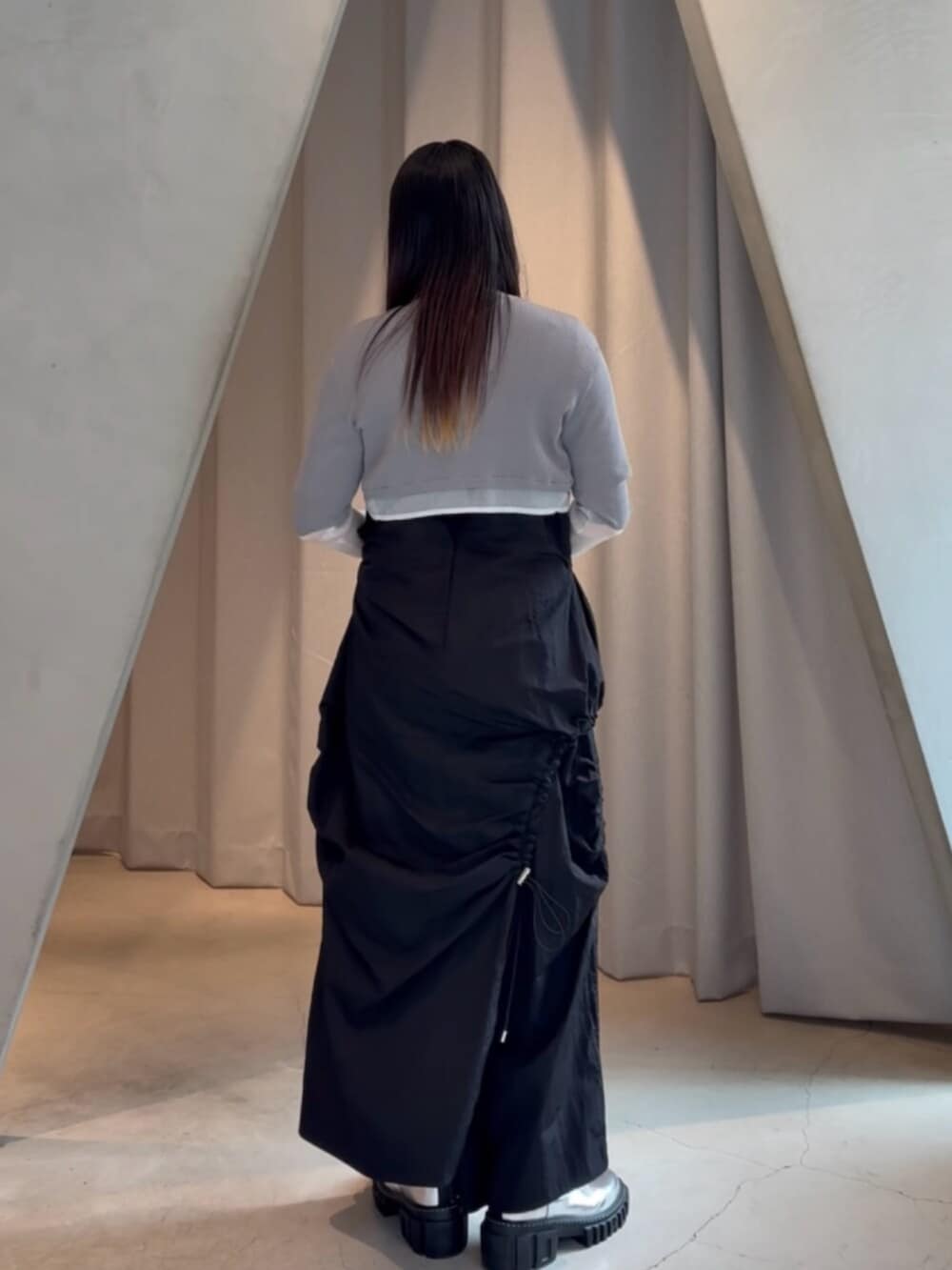 シルバー系のブーツ、ブラック系のワンピース、グレー系のカーディガン/ボレロを着用したレディースの春コーディネートの3枚目の写真