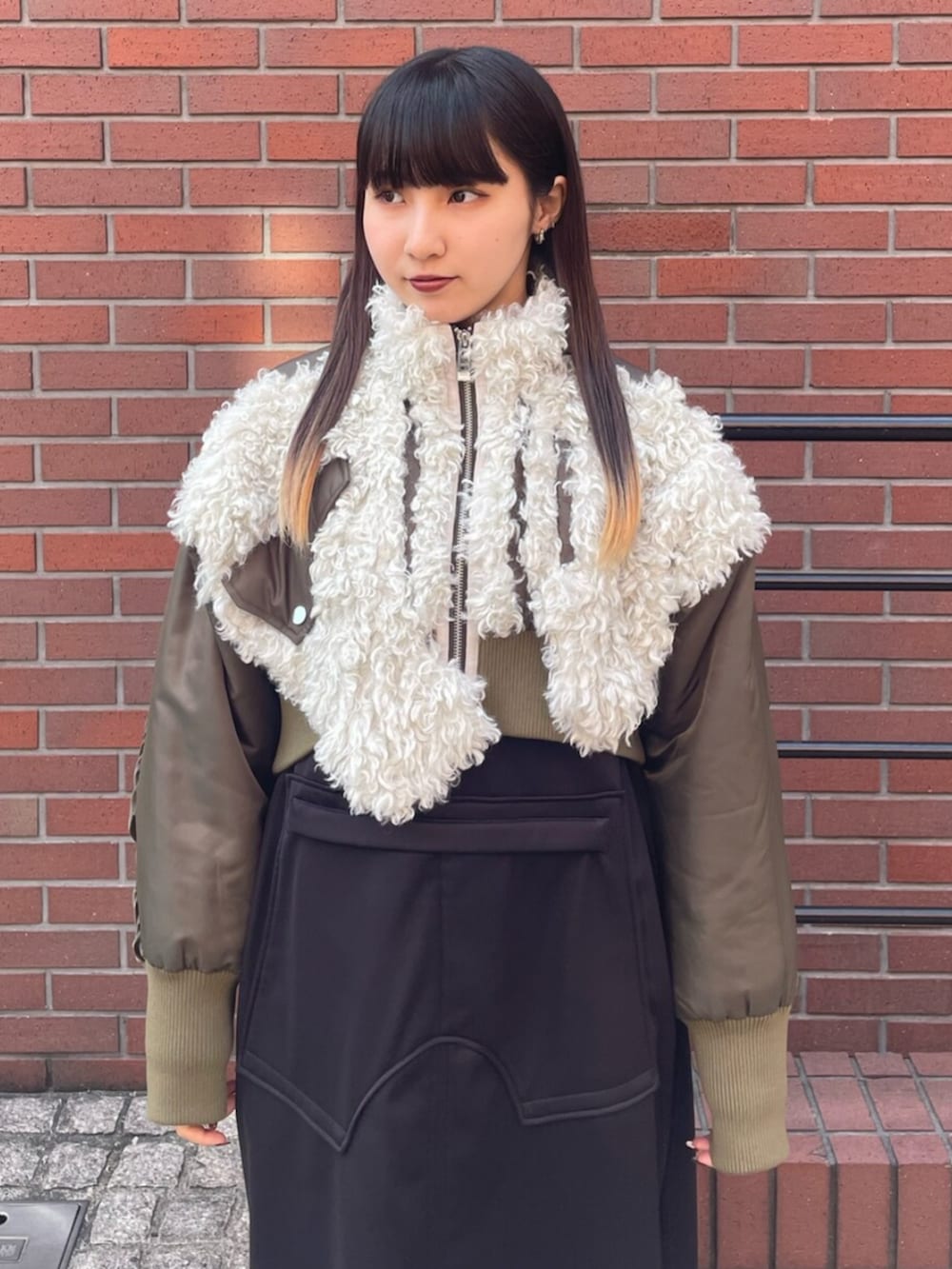 グリーン系のブルゾン、ブラック系のワンピース、ブラック系のブーツを着用したレディースの冬コーディネートの2枚目の写真