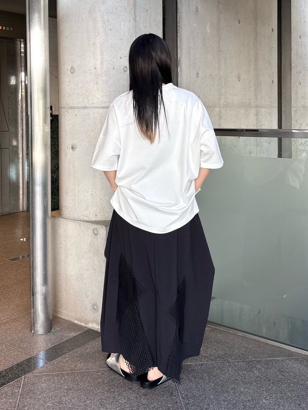 シルバー系のサンダル、ホワイト系のTシャツ/カットソー、ブラック系のスカートを着用したレディースの春コーディネートの3枚目の写真
