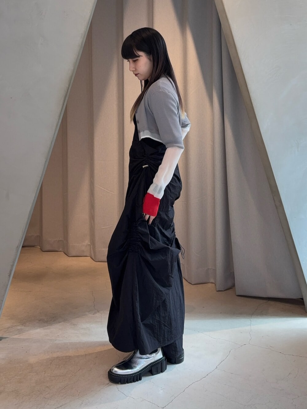 シルバー系のブーツ、ブラック系のワンピース、グレー系のカーディガン/ボレロを着用したレディースの春コーディネートの2枚目の写真