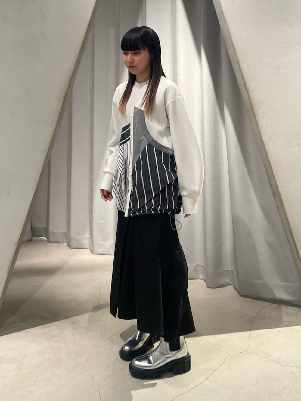 ブラック系のスカート、シルバー系のブーツ、その他のTシャツ/カットソーを着用したレディースの冬コーディネートの2枚目の写真