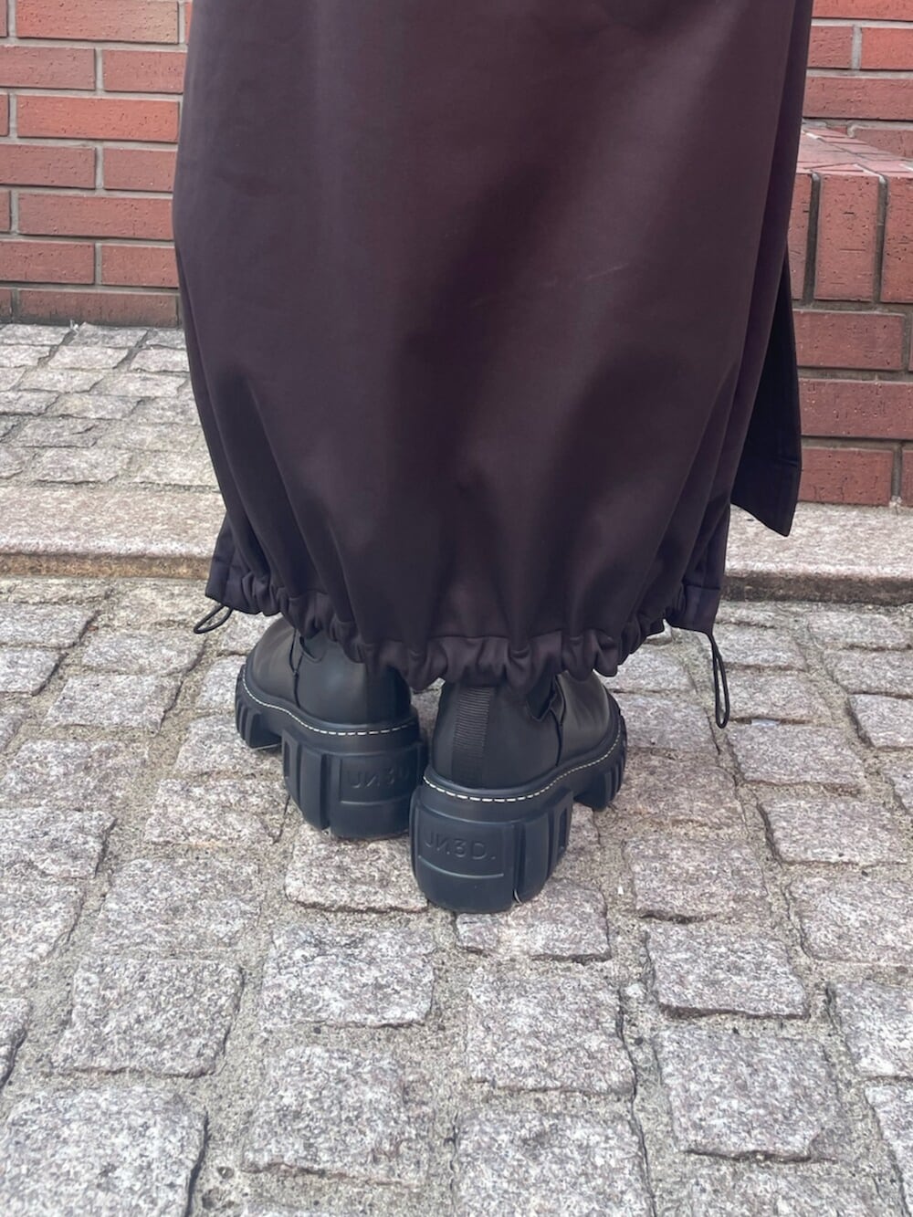 グリーン系のブルゾン、ブラック系のワンピース、ブラック系のブーツを着用したレディースの冬コーディネートの6枚目の写真