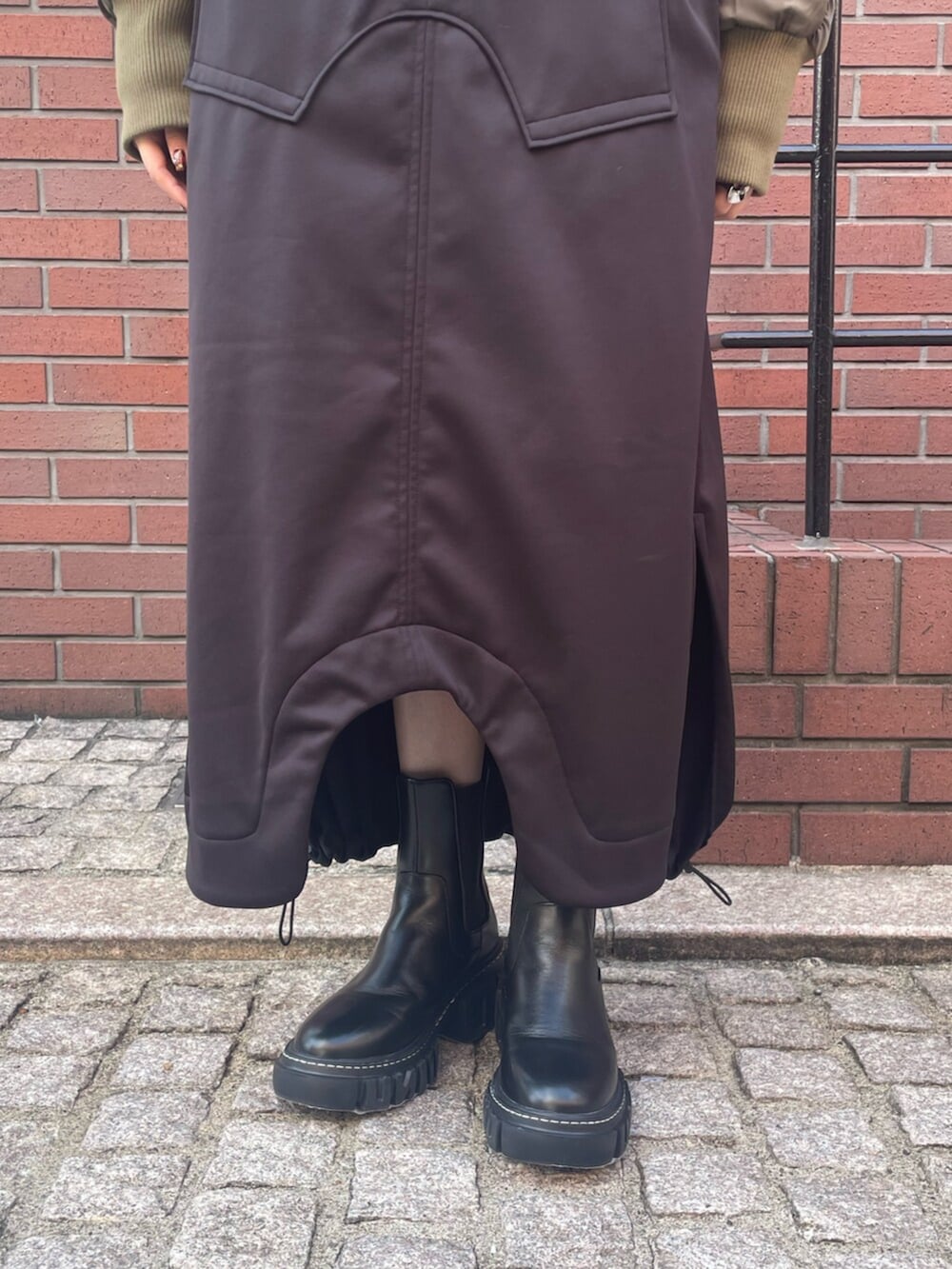 グリーン系のブルゾン、ブラック系のワンピース、ブラック系のブーツを着用したレディースの冬コーディネートの5枚目の写真