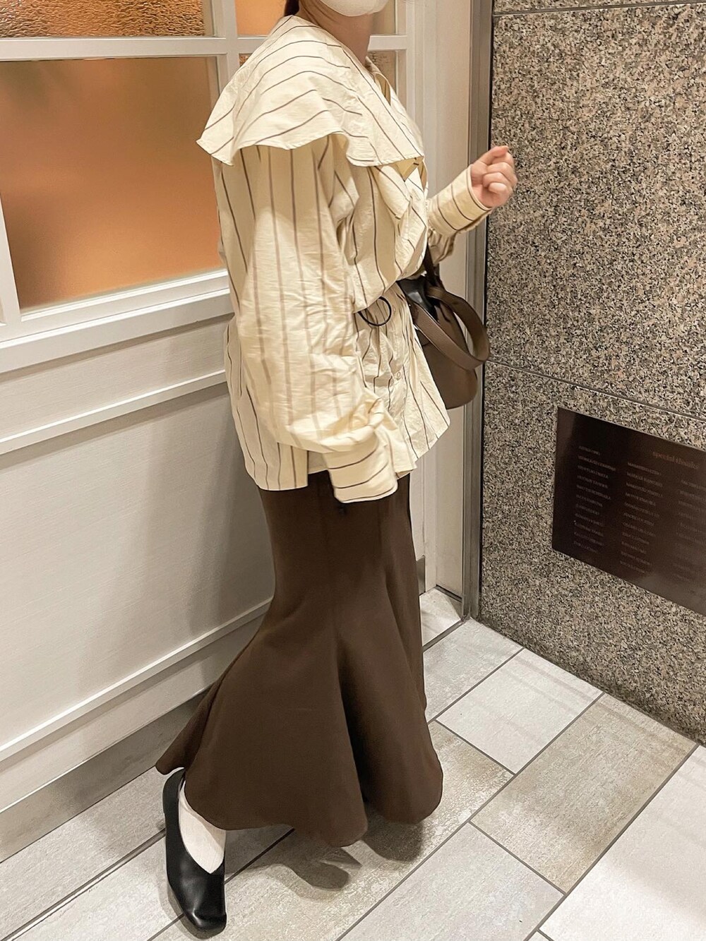 ブラウン系のショルダーバッグ、ブラウン系のスカート、イエロー系のシャツ/ブラウスを着用したレディースの春コーディネートの2枚目の写真