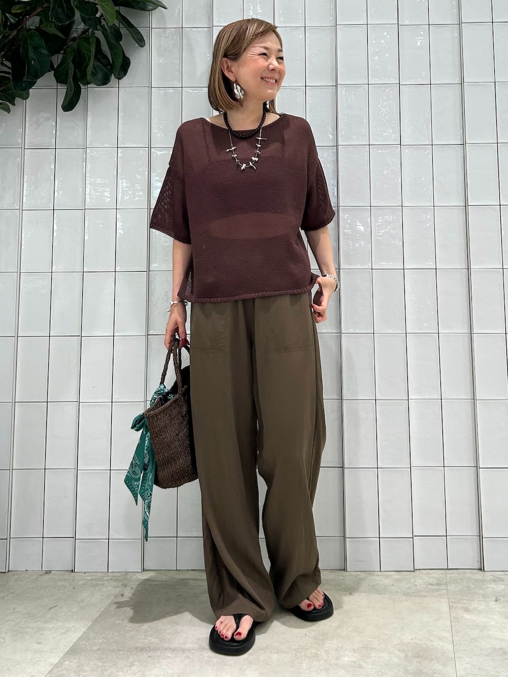 ブラウン系のその他パンツ、ブラウン系のニット/セーター、ブラウン系のかごバッグを着用したレディースの春コーディネートの2枚目の写真