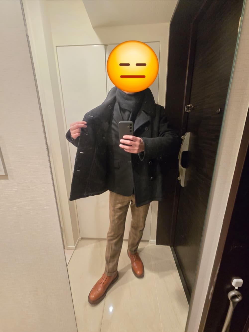 ブラウン系のスラックス、ブラウン系のブーツ、ブラック系のピーコートを着用したメンズの冬コーディネートの2枚目の写真