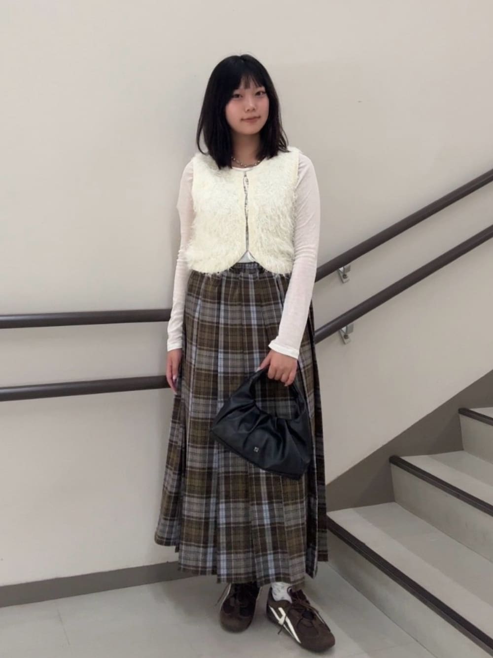 ブラウン系のスカート、ホワイト系のTシャツ/カットソー、ホワイト系のベストを着用したレディースの秋コーディネートの2枚目の写真