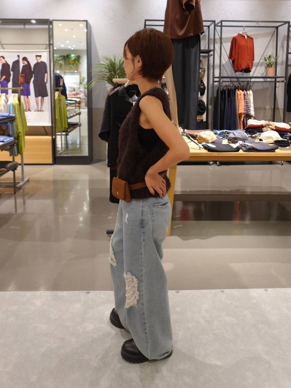 ブルー系のデニムパンツ、ブラウン系のベスト、イエロー系のベルトを着用したレディースの夏コーディネートの5枚目の写真