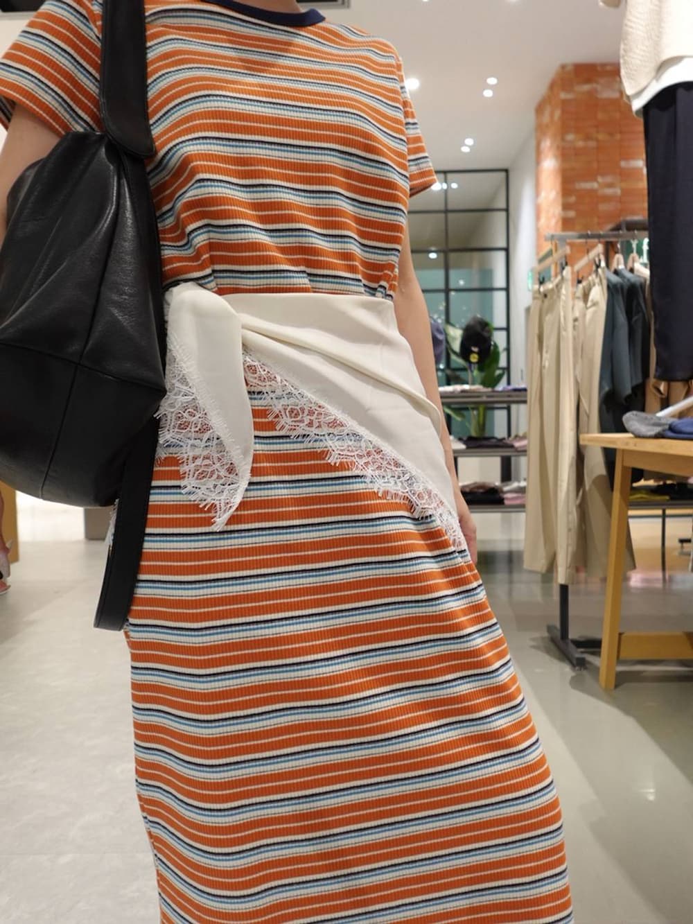 ブルー系のデニムパンツ、シルバー系のサンダル、オレンジ系のワンピースを着用したレディースの春コーディネートの4枚目の写真
