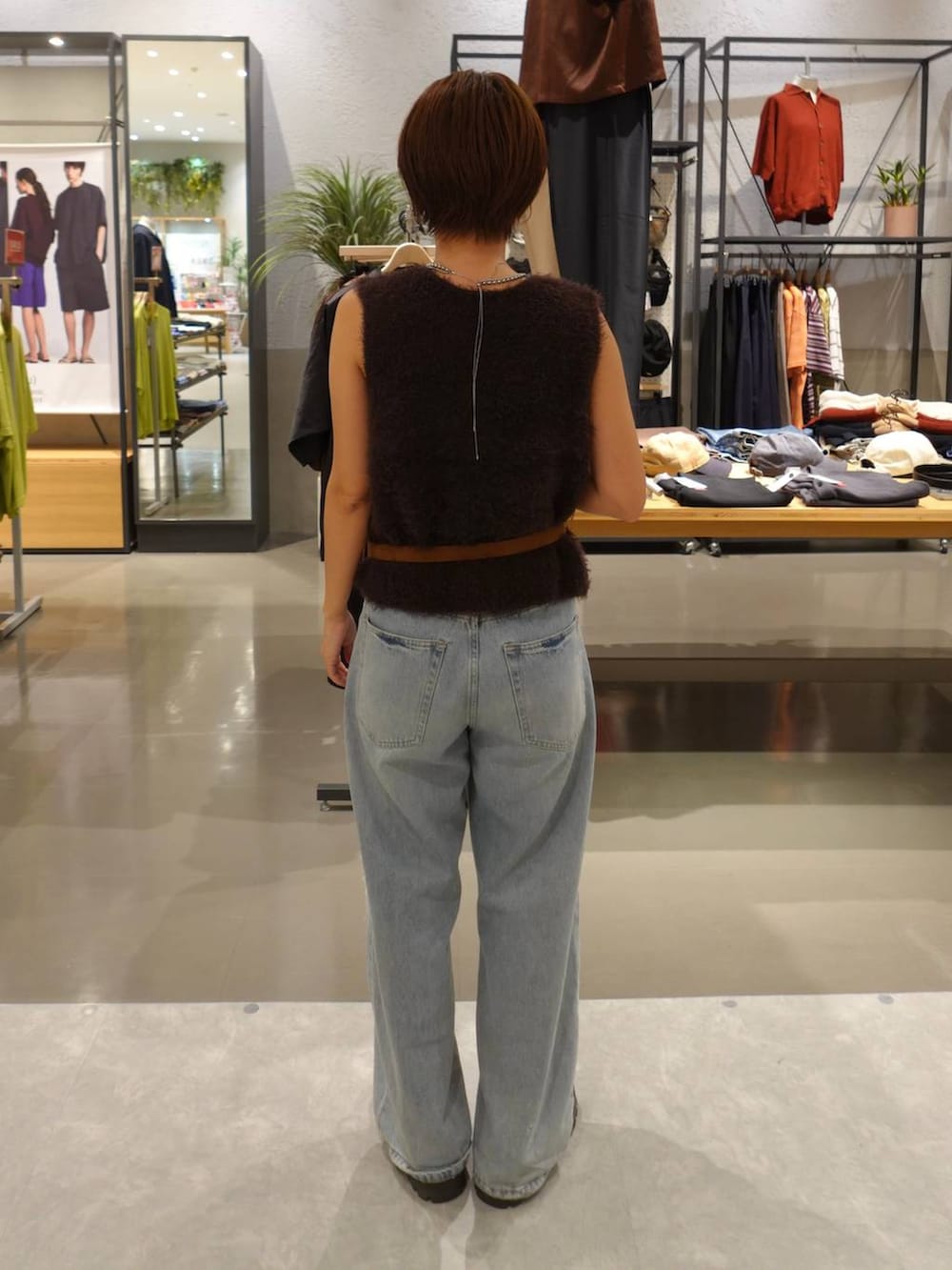 ブルー系のデニムパンツ、ブラウン系のベスト、イエロー系のベルトを着用したレディースの夏コーディネートの4枚目の写真