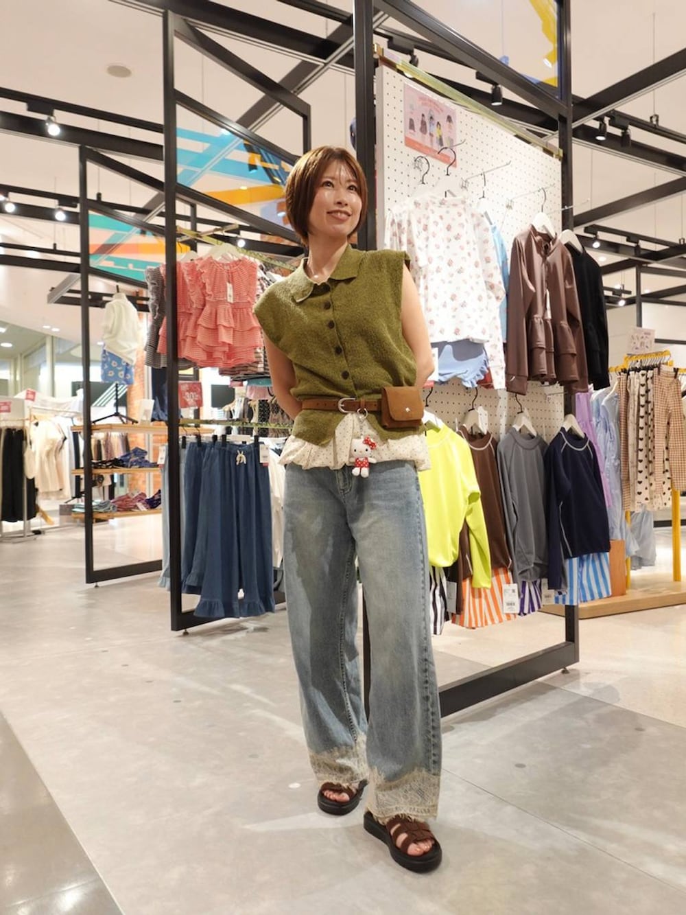 グリーン系のベスト、ブルー系のデニムパンツ、ブラウン系のサンダルを着用したレディースの夏コーディネートの2枚目の写真