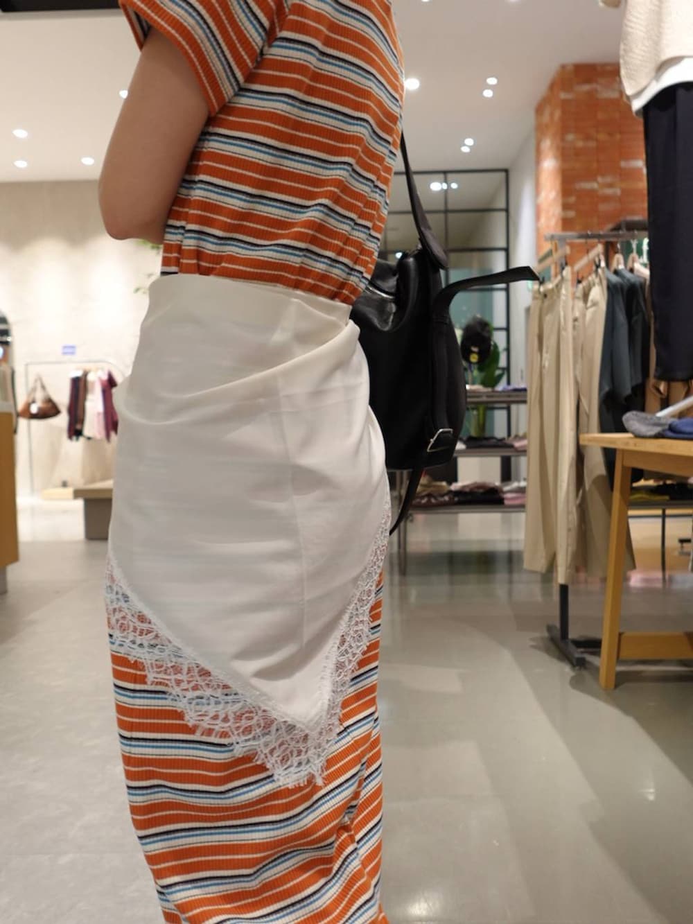 ブルー系のデニムパンツ、シルバー系のサンダル、オレンジ系のワンピースを着用したレディースの春コーディネートの5枚目の写真