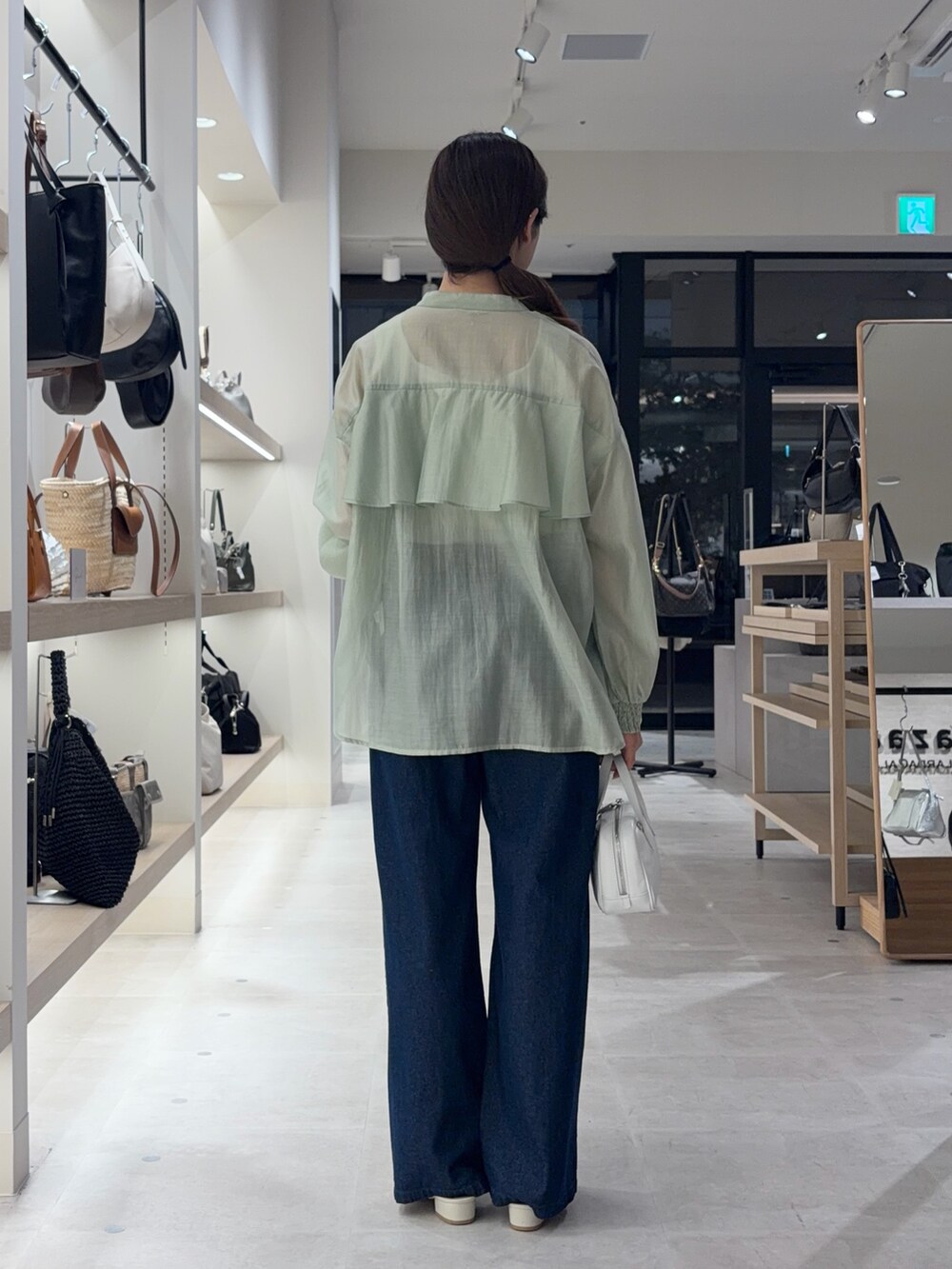 ホワイト系のキャミソール、グリーン系のシャツ/ブラウス、ブルー系のデニムパンツを着用したレディースの夏コーディネートの2枚目の写真