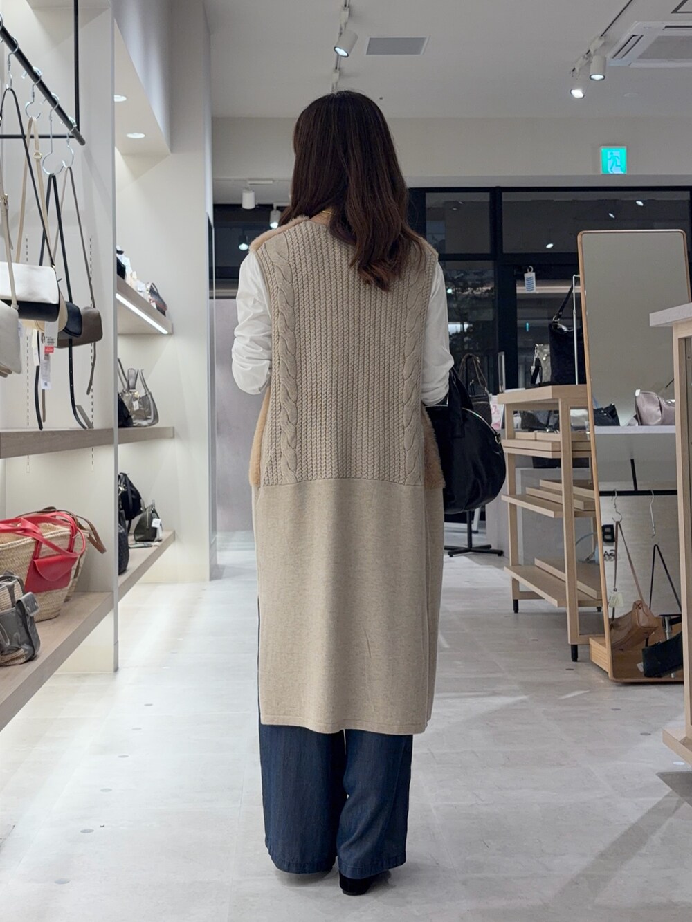 ベージュ系のベスト、ホワイト系のTシャツ/カットソー、ブルー系のデニムパンツを着用したレディースの秋コーディネートの2枚目の写真