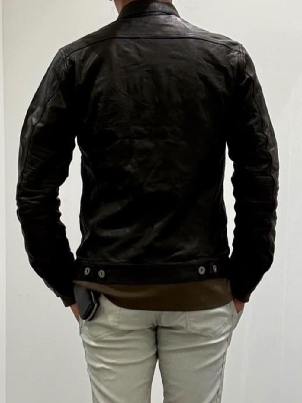 グレー系のチェスターコート、ブラック系のライダースジャケット、グリーン系のTシャツ/カットソーを着用したメンズの秋コーディネートの6枚目の写真