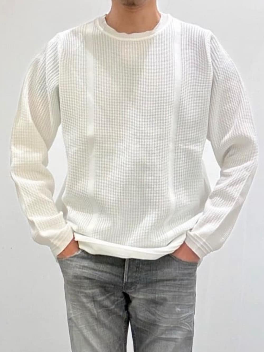 ホワイト系のスニーカー、ホワイト系のニット/セーター、グレー系のデニムパンツを着用したメンズの秋コーディネートの6枚目の写真