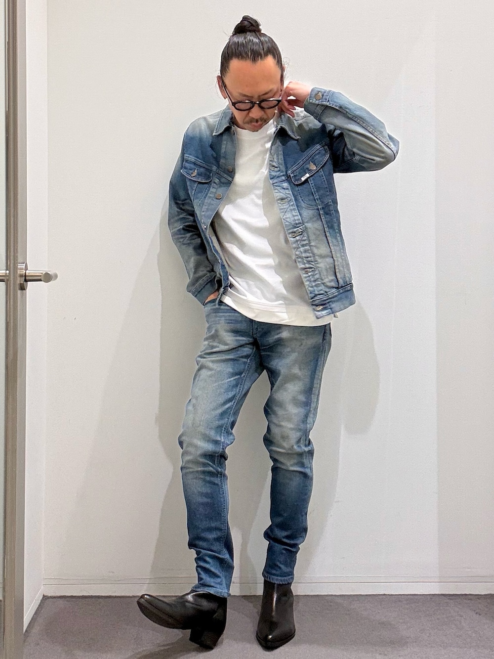 ブルー系のデニムジャケット、ブルー系のデニムパンツ、ブラック系のブーツを着用したメンズの春コーディネートの2枚目の写真