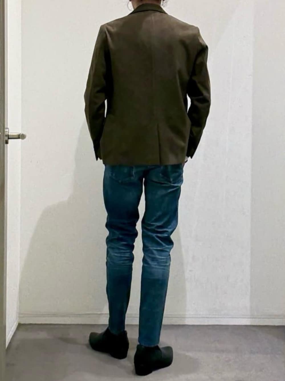 グリーン系のテーラードジャケット、ブルー系のデニムパンツ、ブラック系のスリッポンを着用したメンズの春コーディネートの3枚目の写真