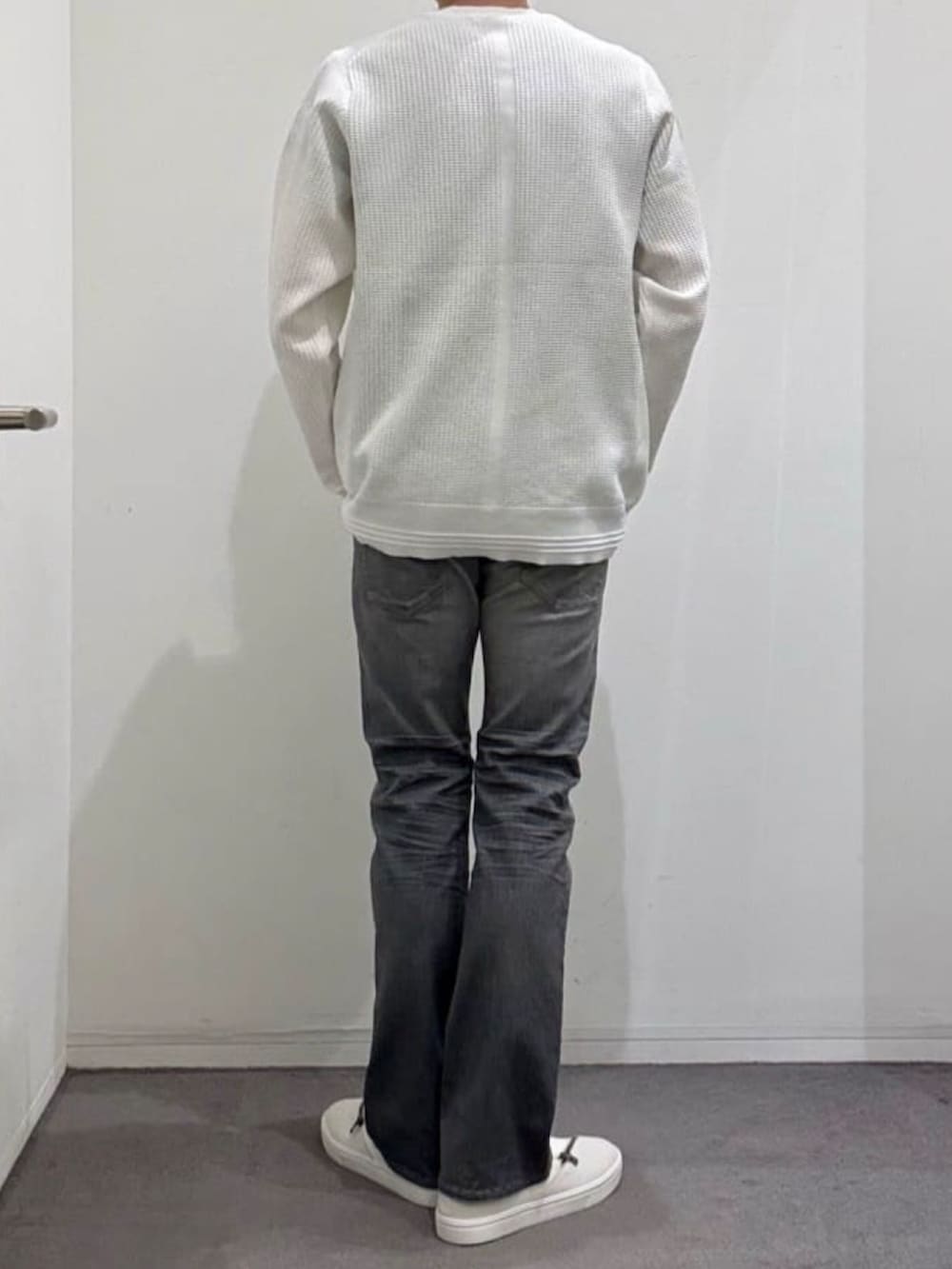 ホワイト系のスニーカー、ホワイト系のニット/セーター、グレー系のデニムパンツを着用したメンズの秋コーディネートの3枚目の写真