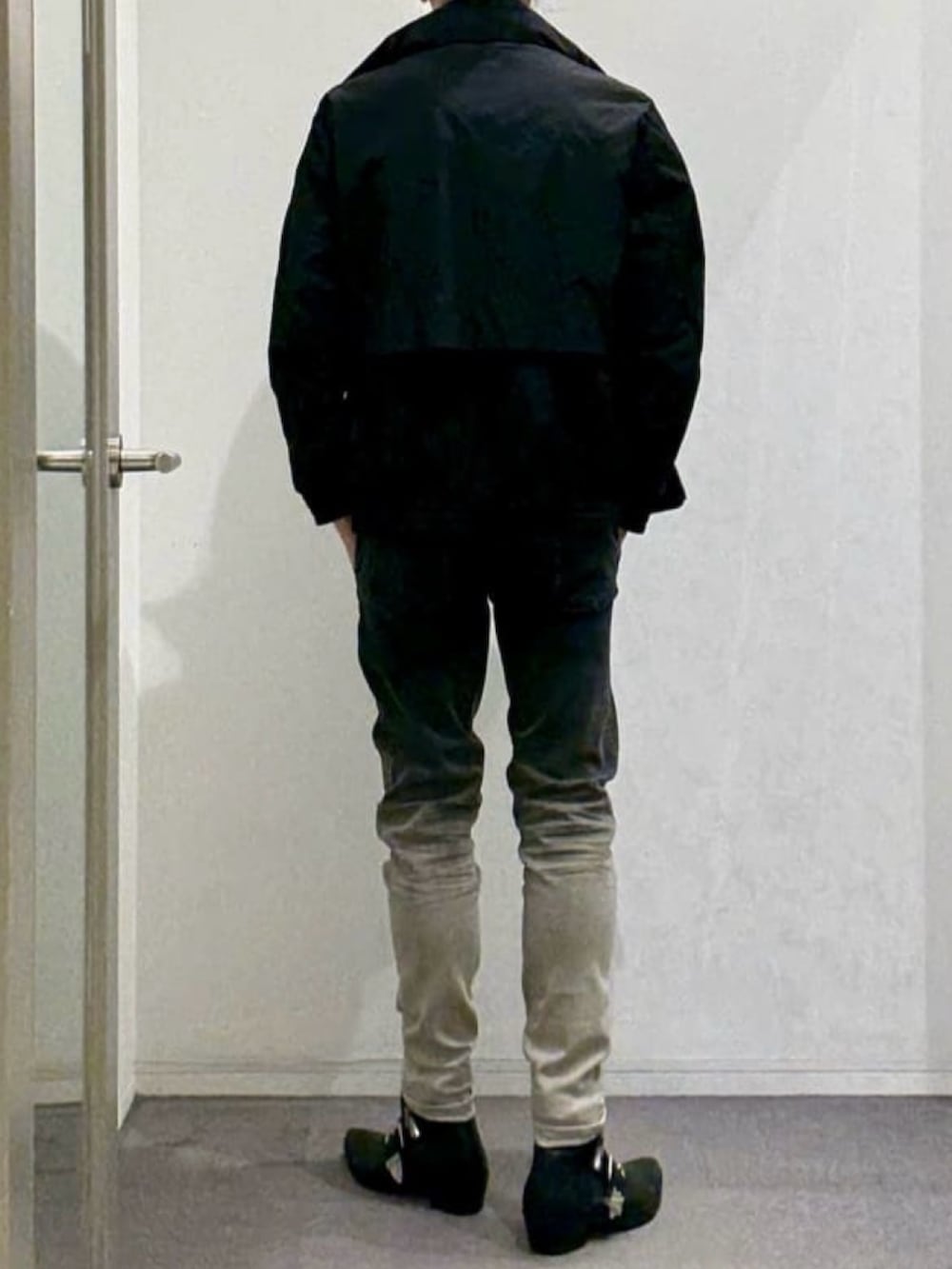 ブラック系のブルゾン、ベージュ系のTシャツ/カットソー、ブラック系のブーツを着用したメンズの春コーディネートの3枚目の写真