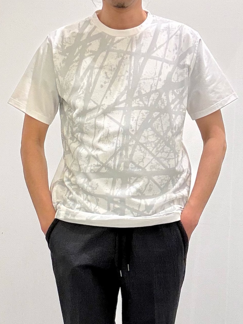 ホワイト系のTシャツ/カットソー、グレー系のテーラードジャケット、ブラック系のスリッポンを着用したメンズの春コーディネートの7枚目の写真