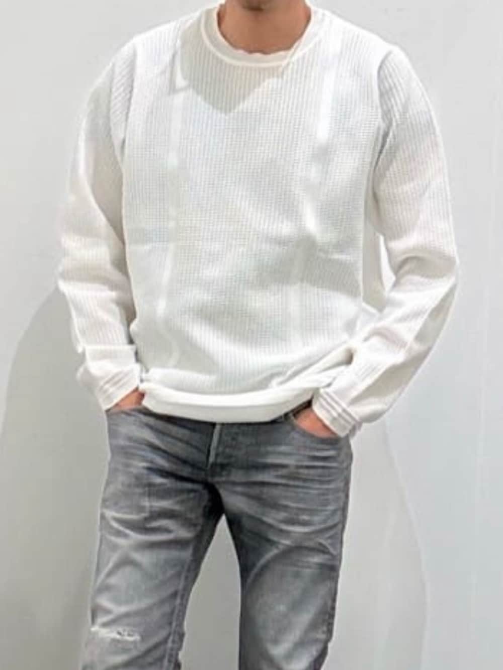 ホワイト系のスニーカー、ホワイト系のニット/セーター、グレー系のデニムパンツを着用したメンズの秋コーディネートの4枚目の写真