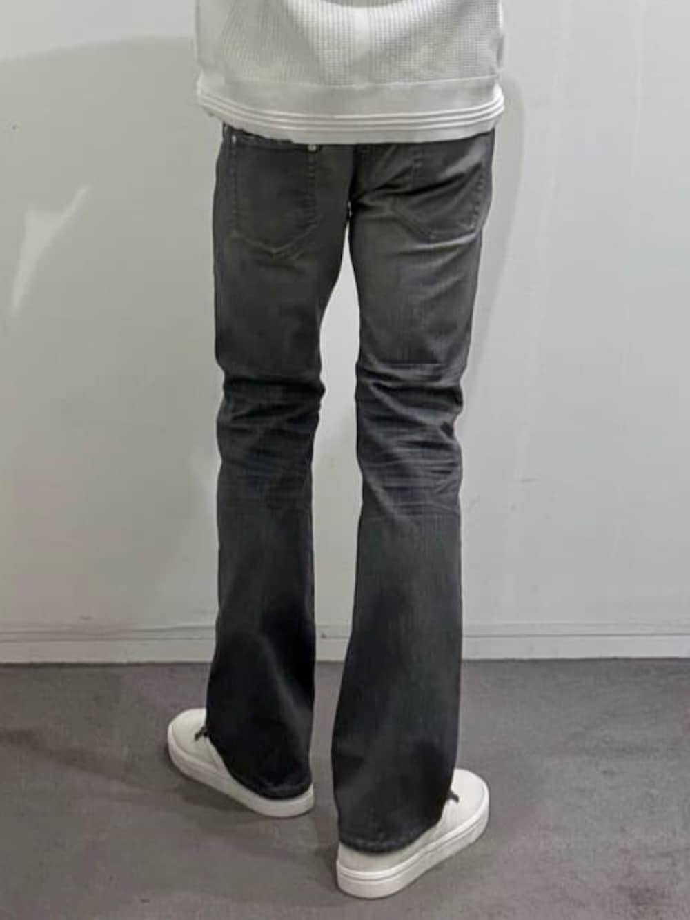 ホワイト系のスニーカー、ホワイト系のニット/セーター、グレー系のデニムパンツを着用したメンズの秋コーディネートの10枚目の写真