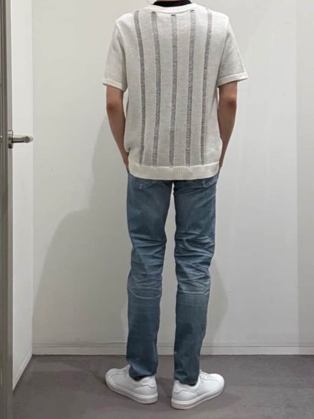 ホワイト系のスニーカー、ホワイト系のニット/セーター、ブルー系のデニムパンツを着用したメンズの春コーディネートの3枚目の写真