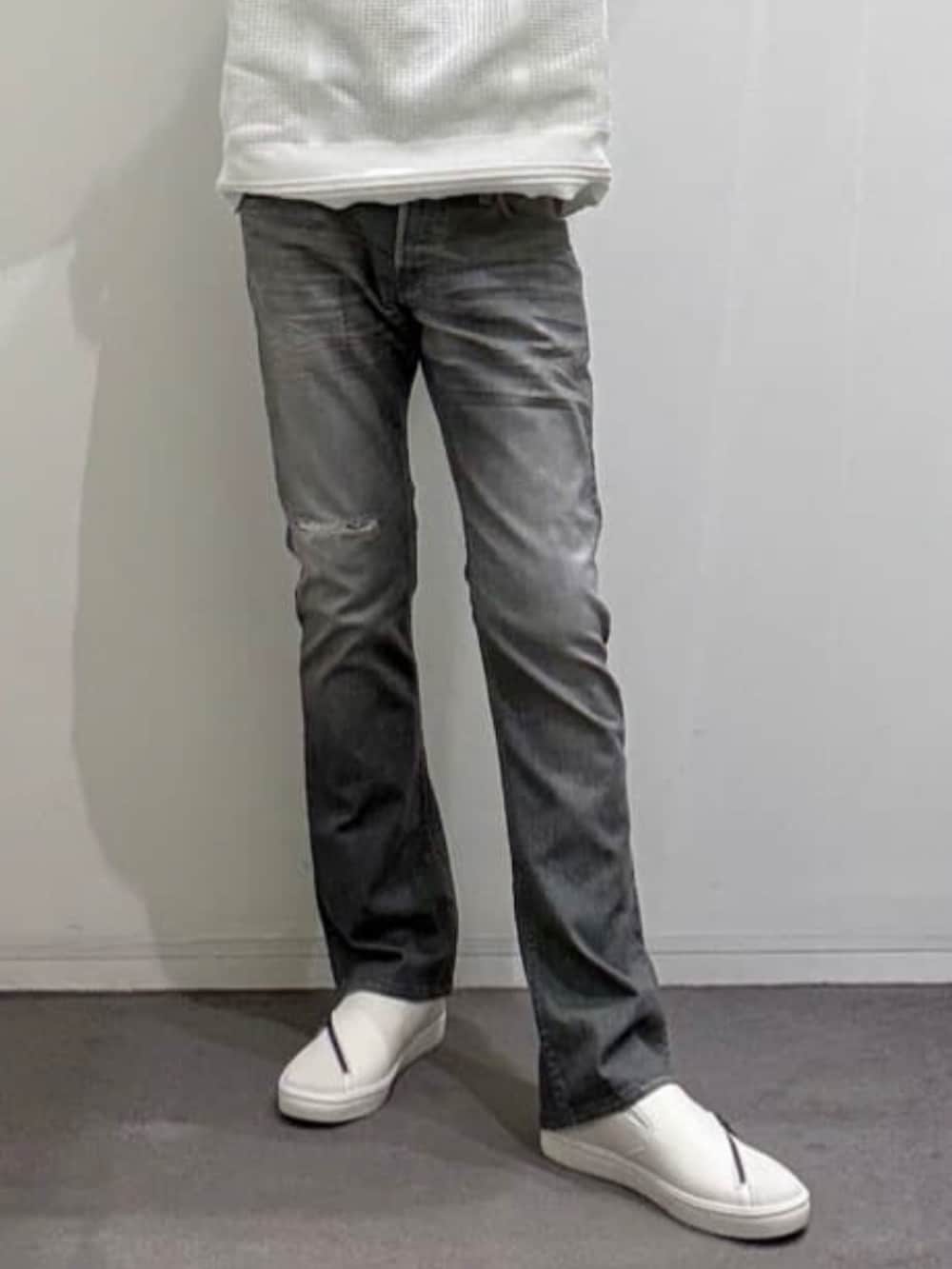 ホワイト系のスニーカー、ホワイト系のニット/セーター、グレー系のデニムパンツを着用したメンズの秋コーディネートの8枚目の写真