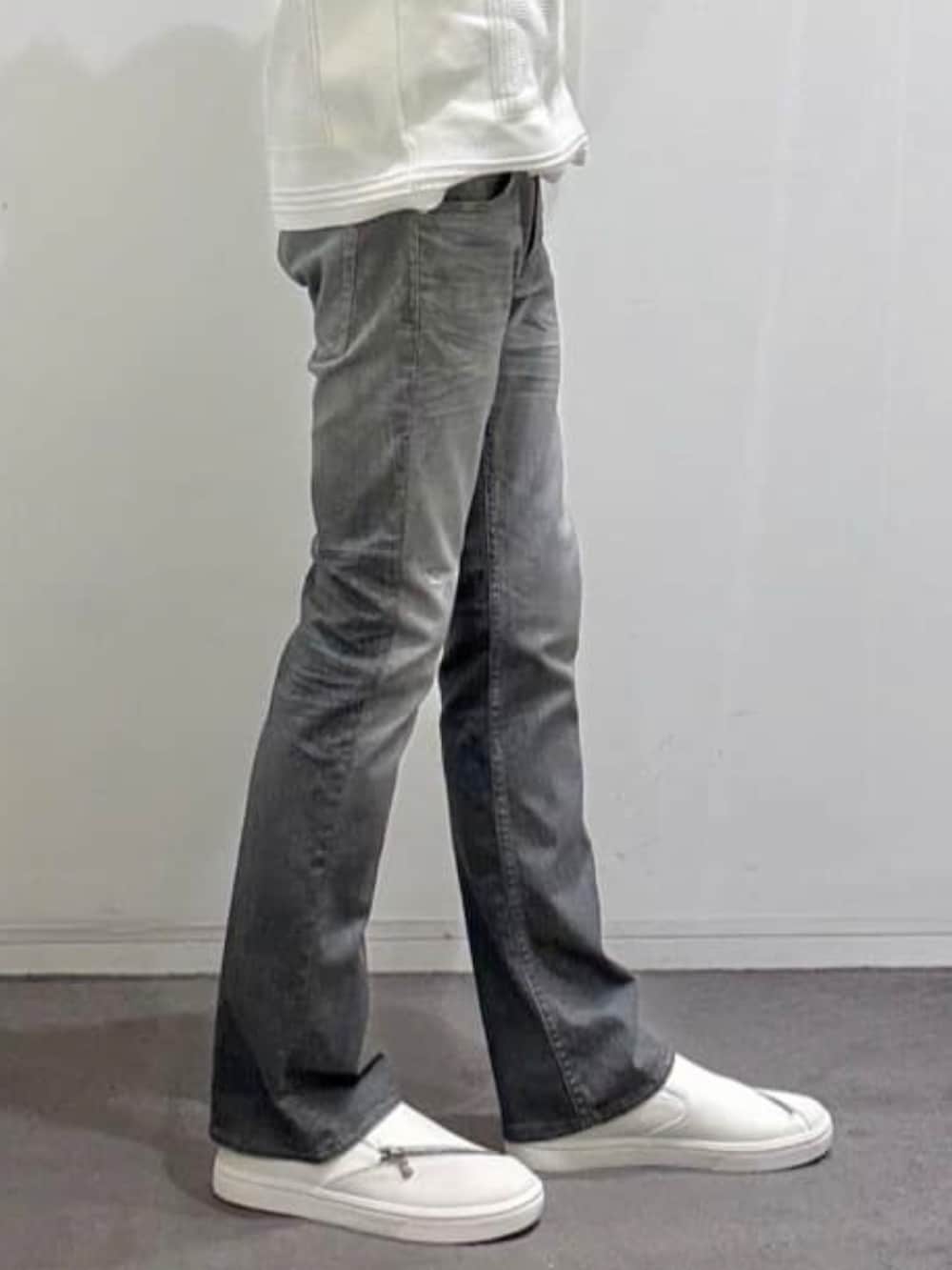 ホワイト系のスニーカー、ホワイト系のニット/セーター、グレー系のデニムパンツを着用したメンズの秋コーディネートの9枚目の写真