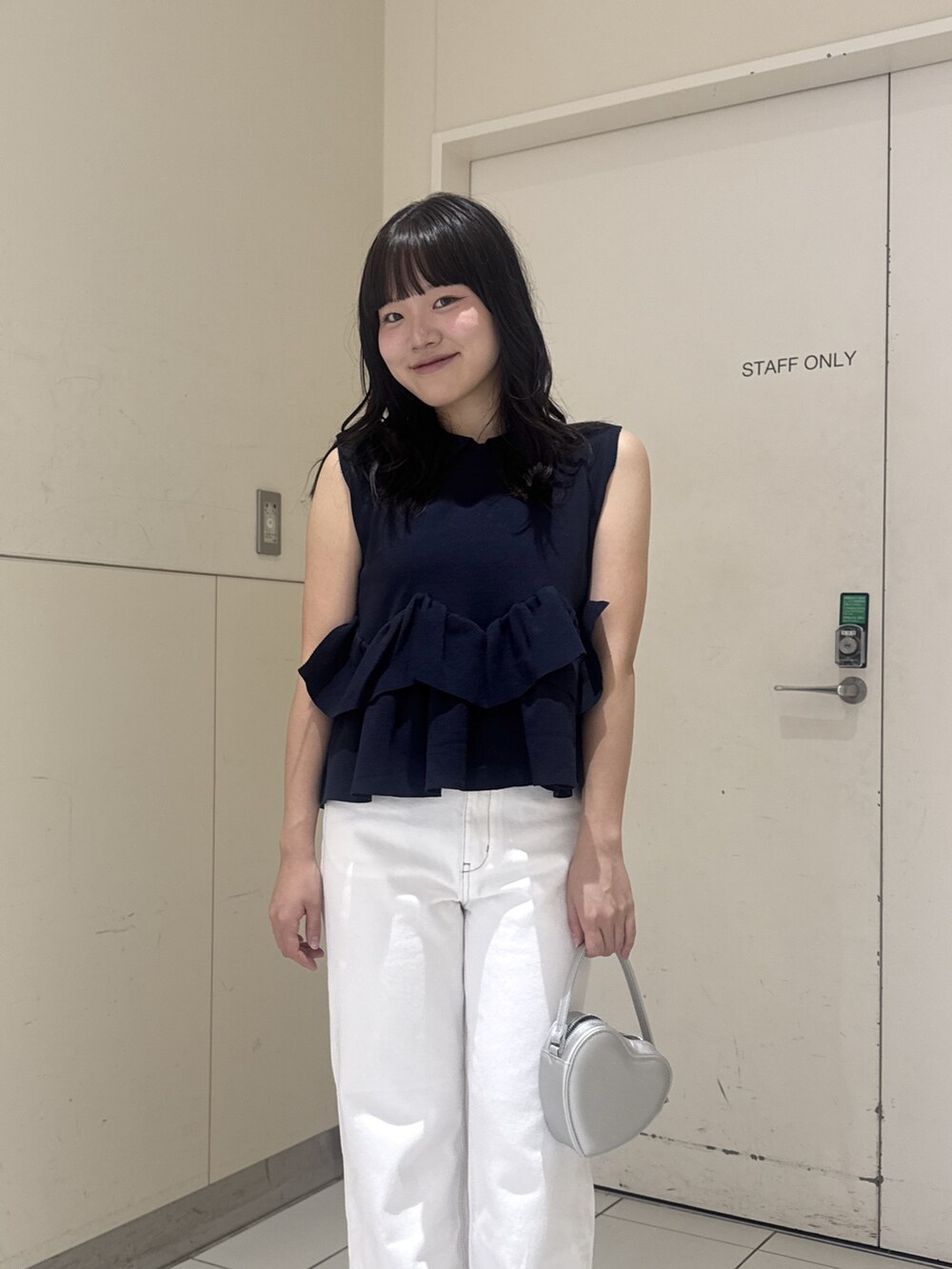ブルー系のニット/セーター、ホワイト系のデニムパンツ、シルバー系のショルダーバッグを着用したレディースの夏コーディネートの5枚目の写真