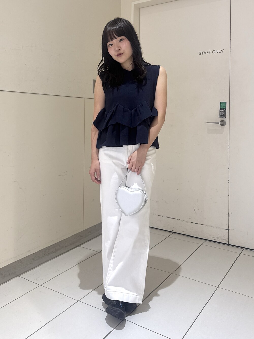 ブルー系のニット/セーター、ホワイト系のデニムパンツ、シルバー系のショルダーバッグを着用したレディースの夏コーディネートの3枚目の写真