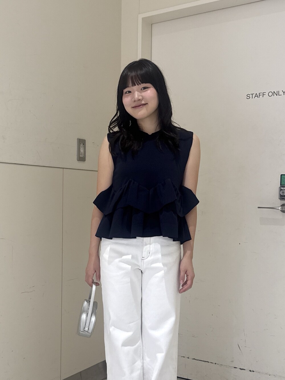 ブルー系のニット/セーター、ホワイト系のデニムパンツ、シルバー系のショルダーバッグを着用したレディースの夏コーディネートの6枚目の写真