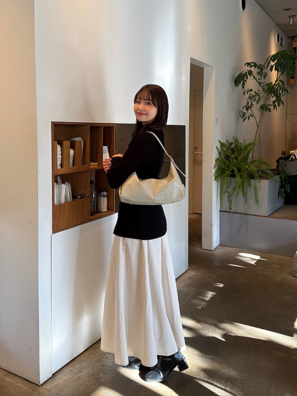 ホワイト系のスカート、ブラック系のニット/セーター、ベージュ系のショルダーバッグを着用したレディースの春コーディネートの2枚目の写真