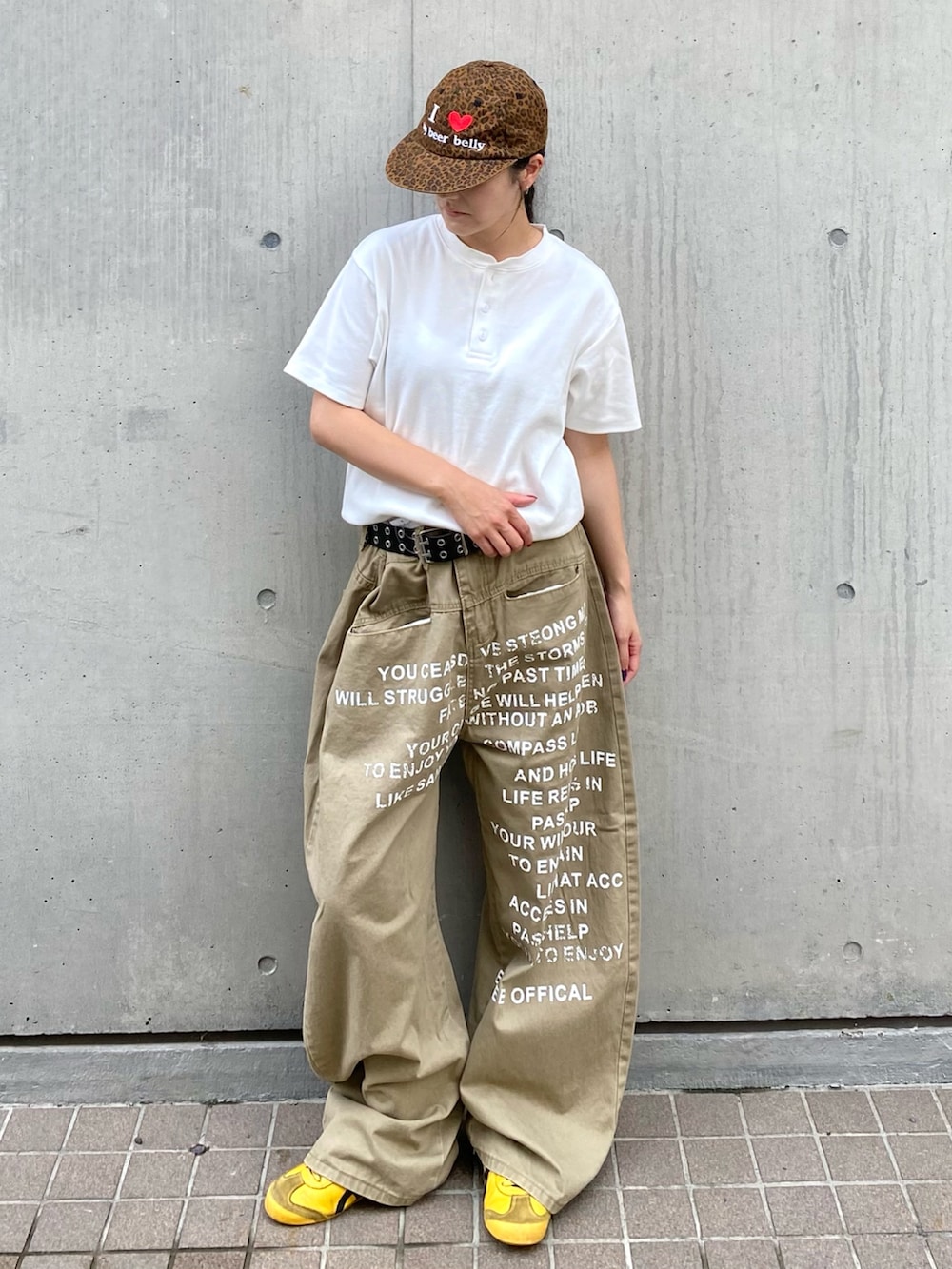 ホワイト系のTシャツ/カットソー、ベージュ系のチノパンツ、ブラウン系のキャップを着用したレディースの夏コーディネートの2枚目の写真