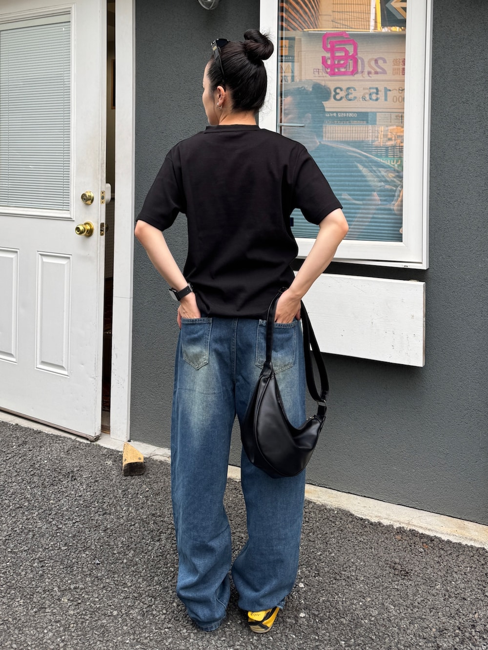ブラック系のTシャツ/カットソー、ブルー系のデニムパンツ、ブラック系のショルダーバッグを着用したレディースの夏コーディネートの2枚目の写真