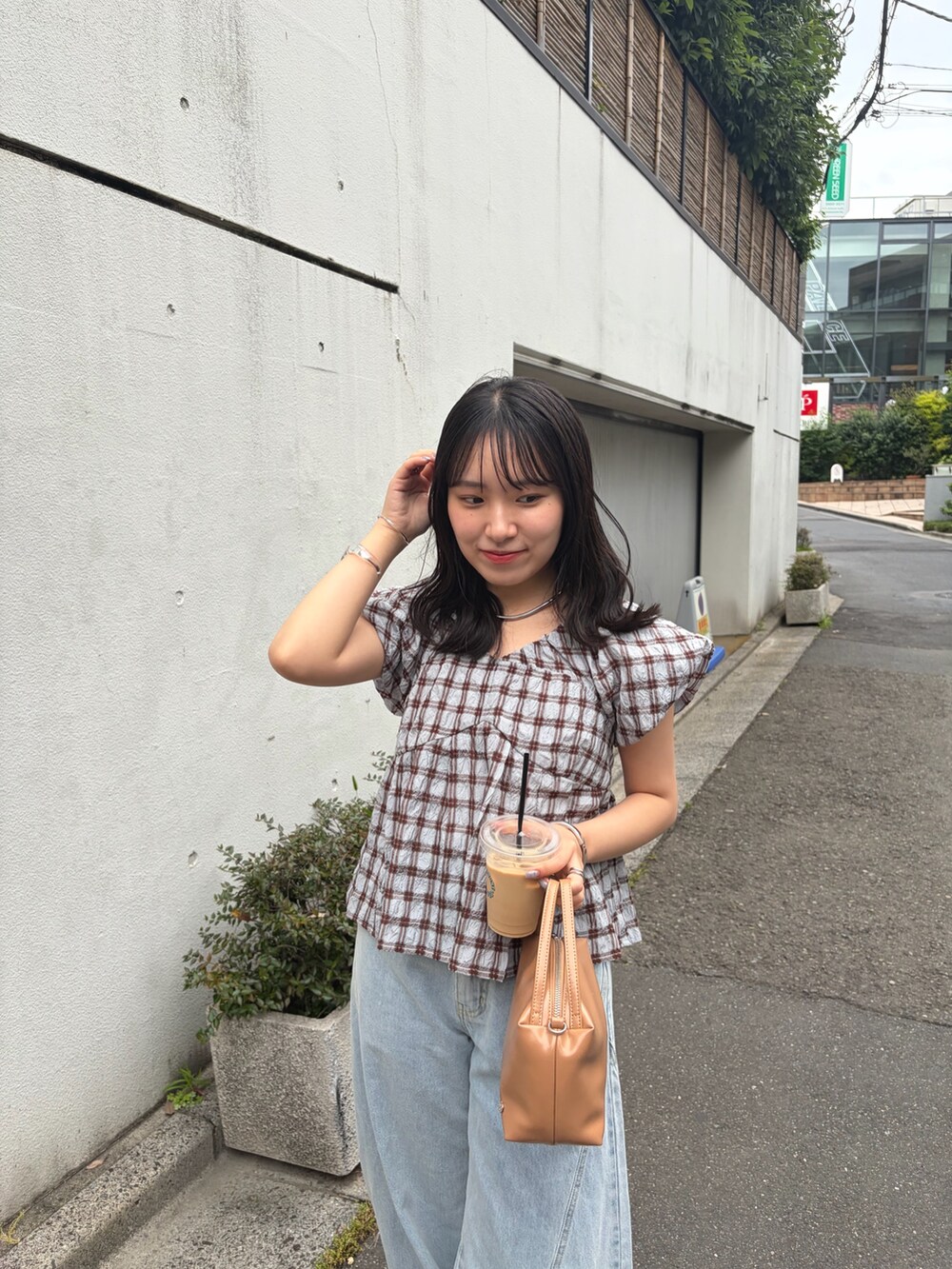 ブラウン系のシャツ/ブラウス、イエロー系のハンドバッグ、ブルー系のデニムパンツを着用したレディースの夏コーディネートの2枚目の写真