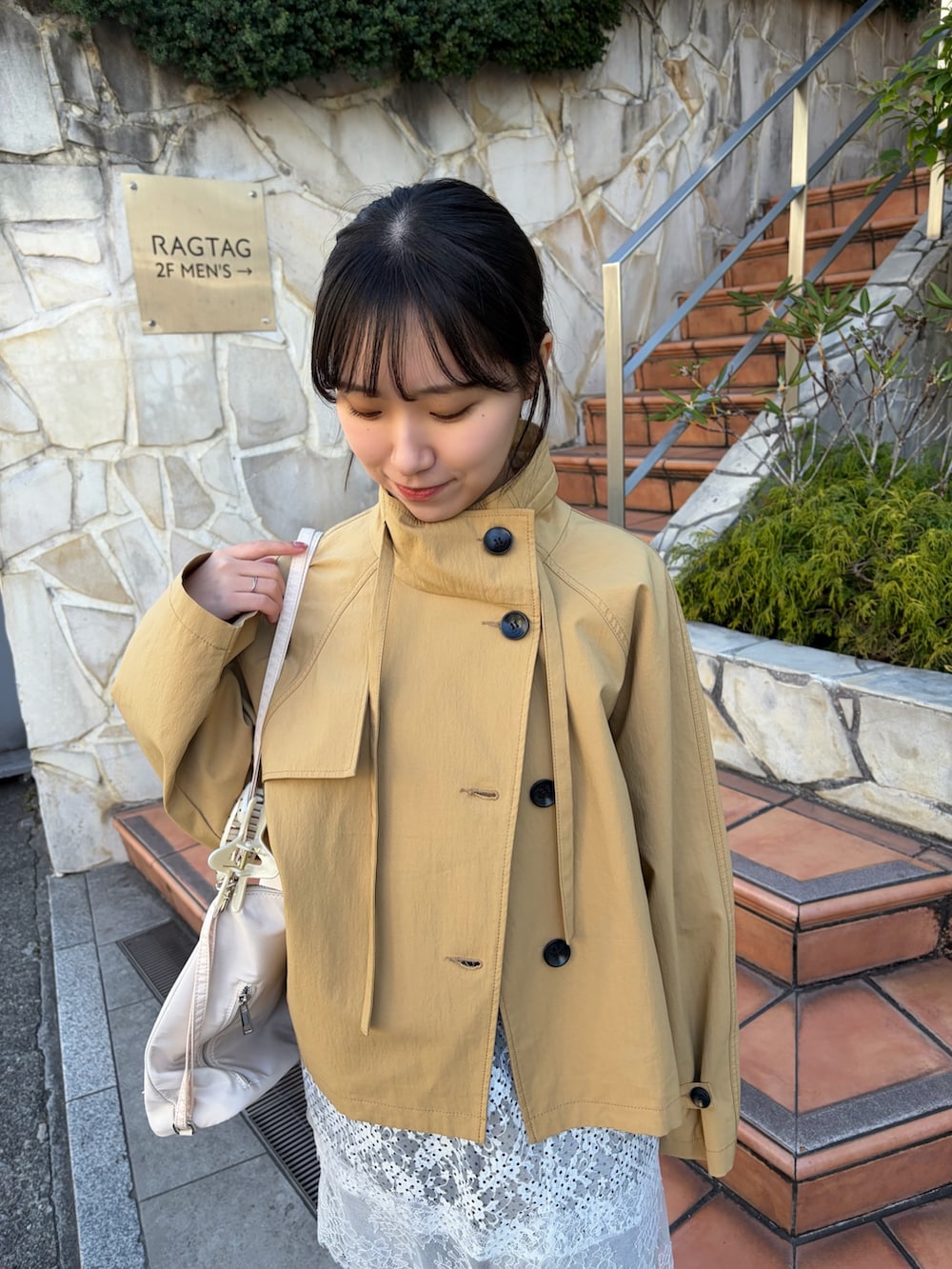 イエロー系のトレンチコート、グレー系のスウェットパンツ、ブラウン系のブーツを着用したレディースの冬コーディネートの3枚目の写真