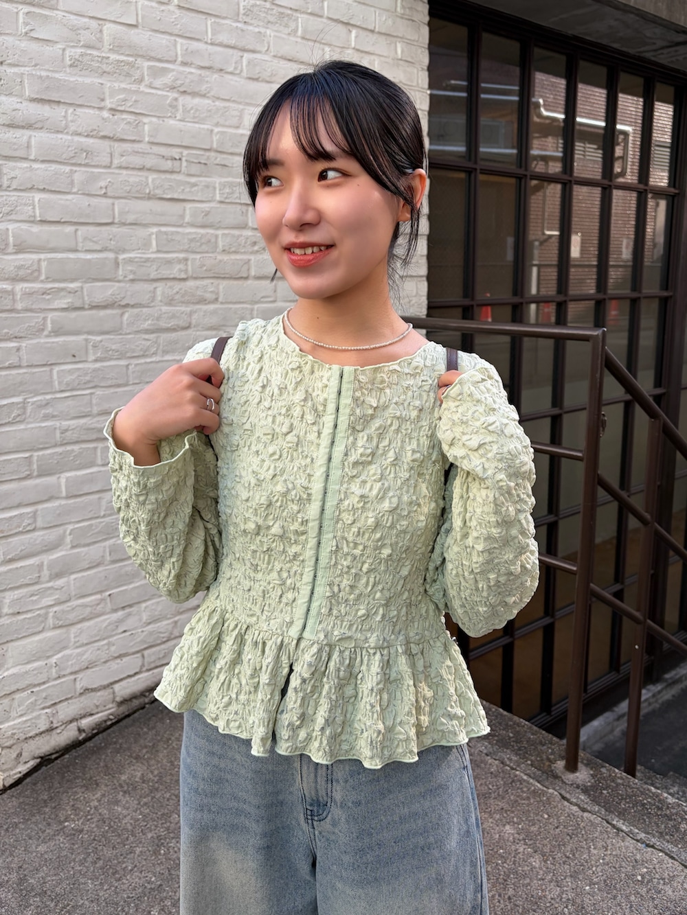 グリーン系のシャツ/ブラウス、イエロー系のトートバッグ、ブルー系のデニムパンツを着用したレディースの冬コーディネートの3枚目の写真