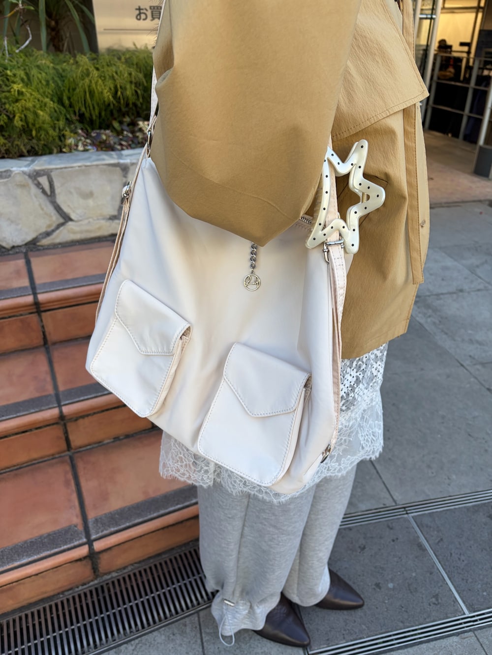 イエロー系のトレンチコート、グレー系のスウェットパンツ、ブラウン系のブーツを着用したレディースの冬コーディネートの6枚目の写真