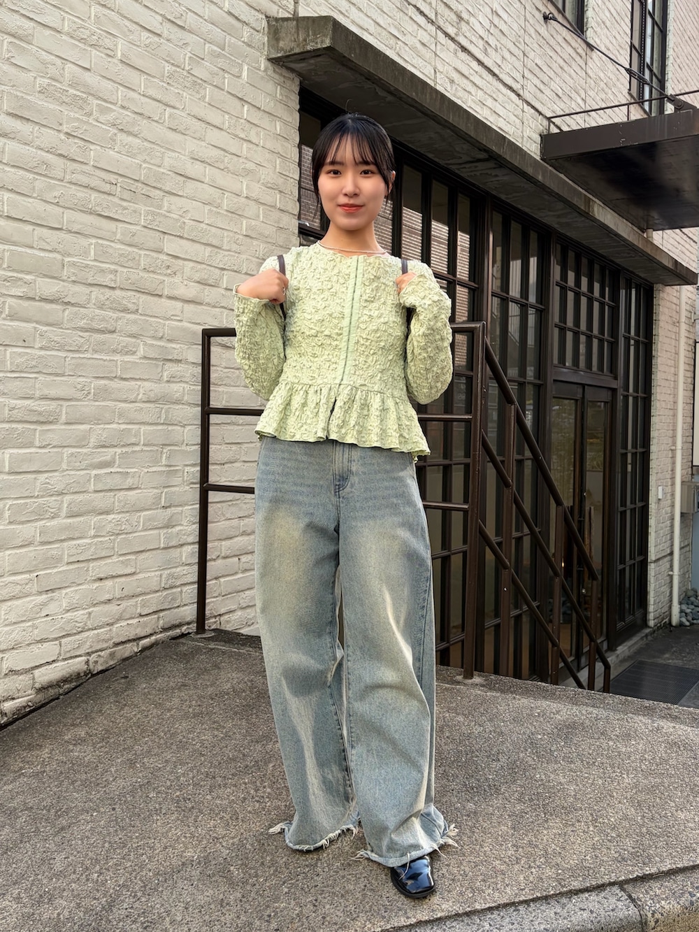 グリーン系のシャツ/ブラウス、イエロー系のトートバッグ、ブルー系のデニムパンツを着用したレディースの冬コーディネートの2枚目の写真