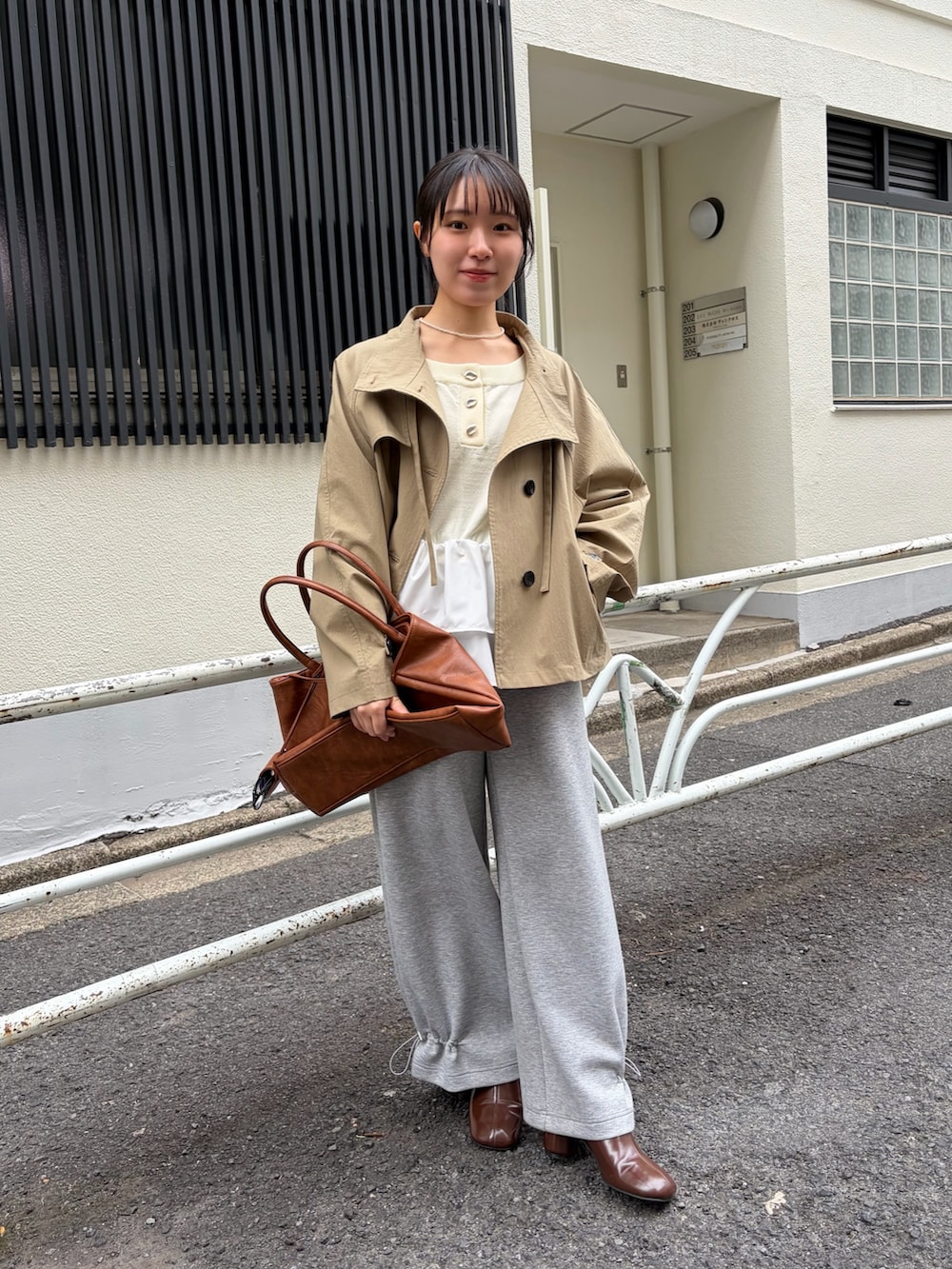 グレー系のスウェットパンツ、ブラウン系のブーツ、イエロー系のトートバッグを着用したレディースの冬コーディネートの2枚目の写真