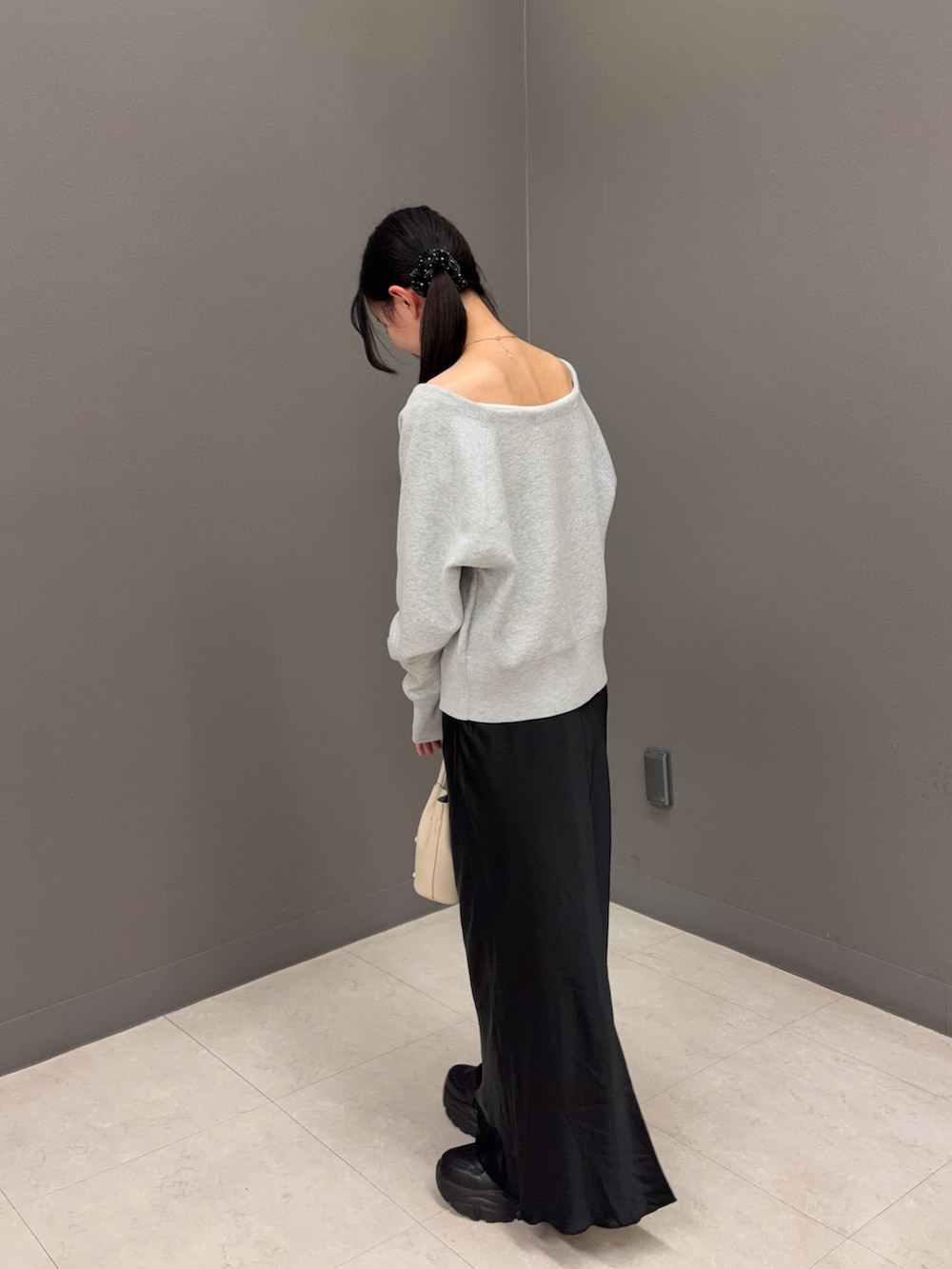 グレー系のニット/セーター、ブラック系のスカート、ホワイト系のハンドバッグを着用したレディースの秋コーディネートの2枚目の写真