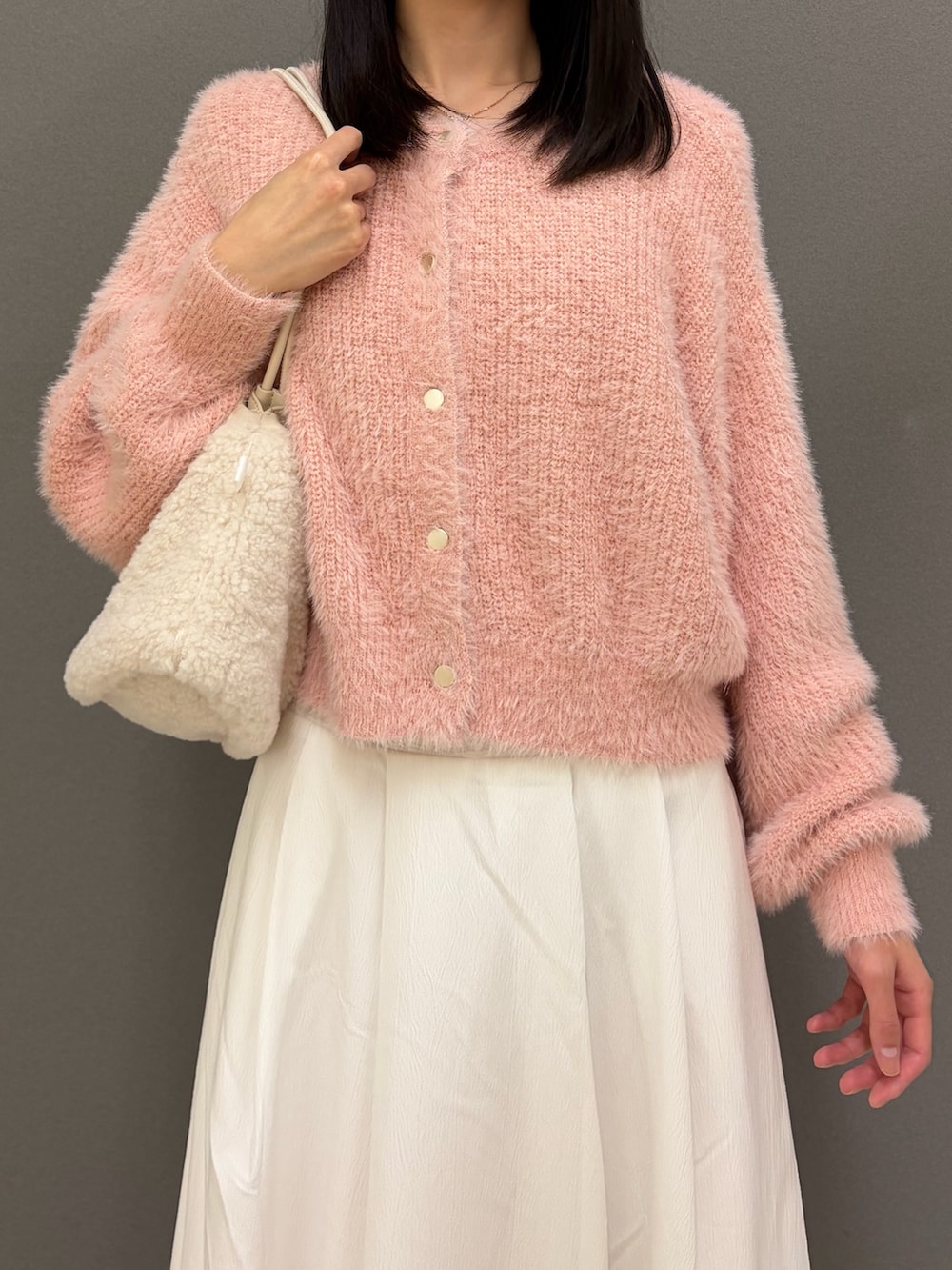 イエロー系のサンダル、ピンク系のカーディガン/ボレロ、ホワイト系のスカートを着用したレディースの秋コーディネートの2枚目の写真
