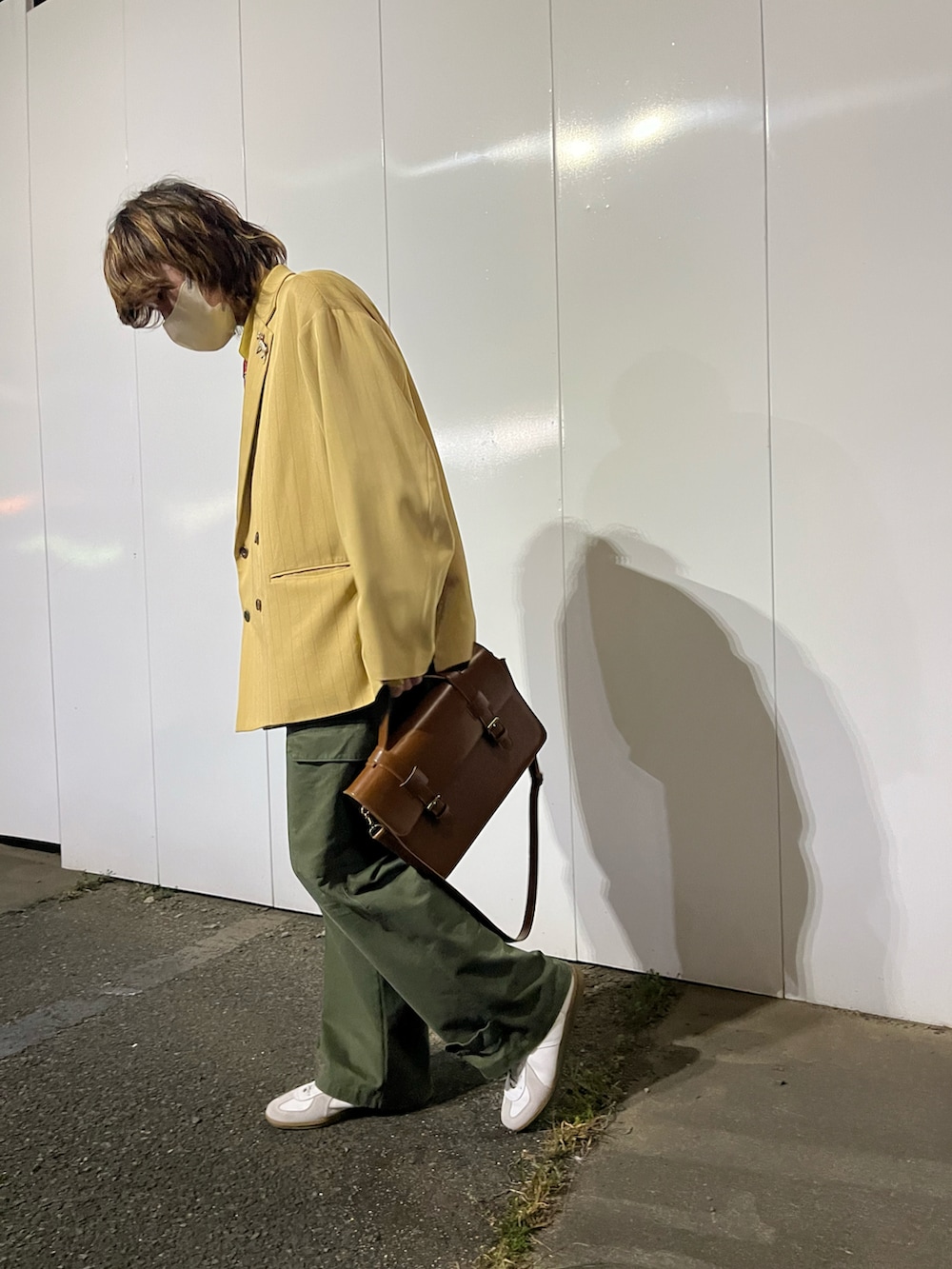ホワイト系のスニーカー、グリーン系のカーゴパンツ、ブラウン系のハンドバッグを着用したメンズの春コーディネートの2枚目の写真