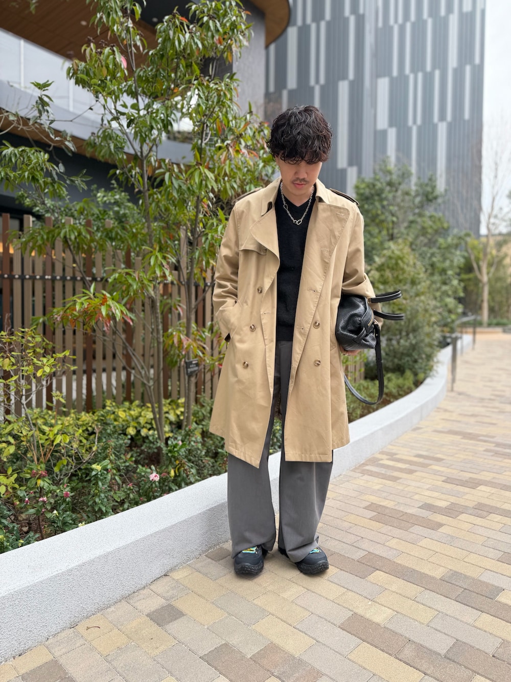 グレー系のニット/セーター、グレー系のスラックス、ブラック系のスニーカーを着用したメンズの春コーディネートの2枚目の写真