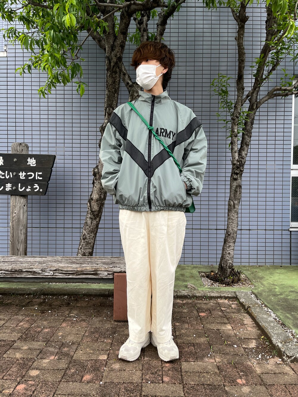 ホワイト系のチノパンツ、ホワイト系のスニーカー、グリーン系のショルダーバッグを着用したメンズの春コーディネートの2枚目の写真