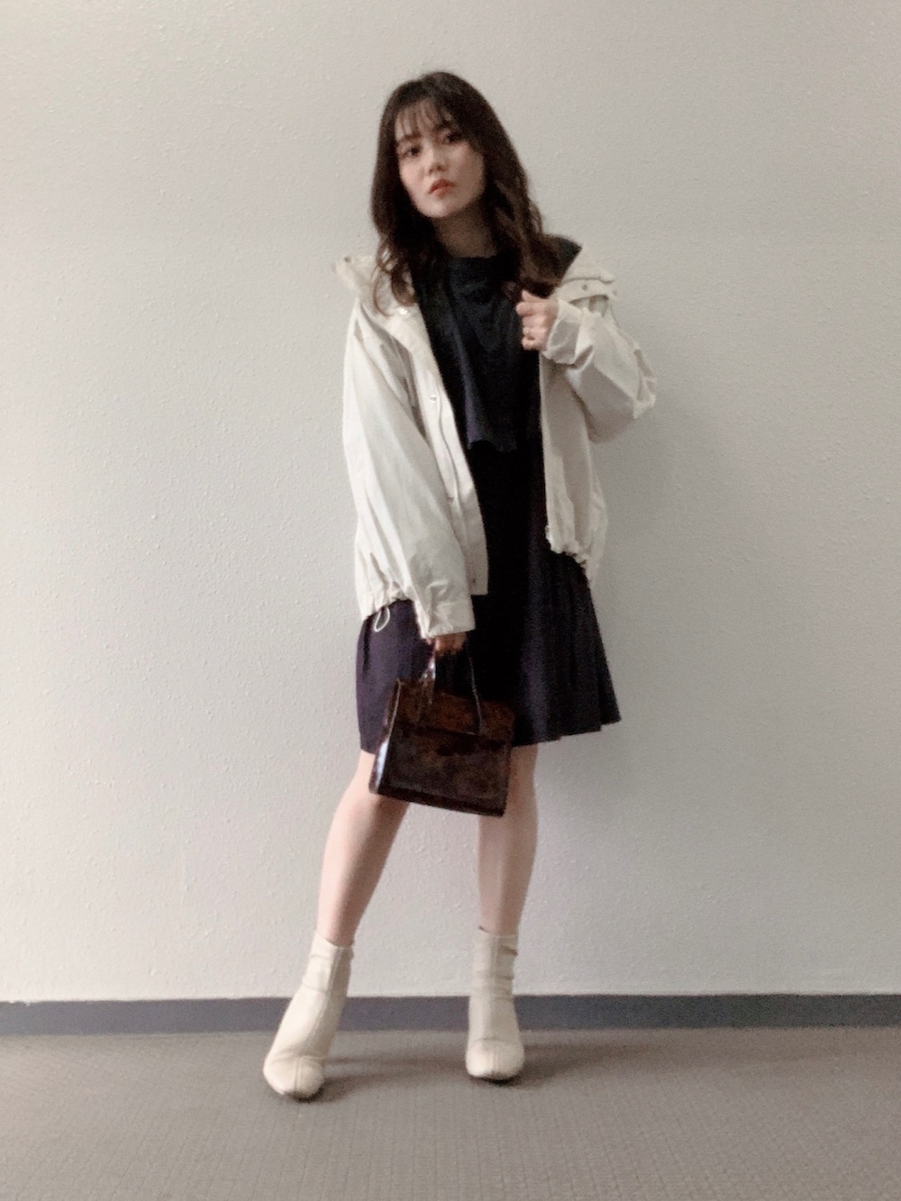 ブラウン系のハンドバッグ、ホワイト系のブーツ、ブラック系のシャツ/ブラウスを着用したレディースの春コーディネートの2枚目の写真