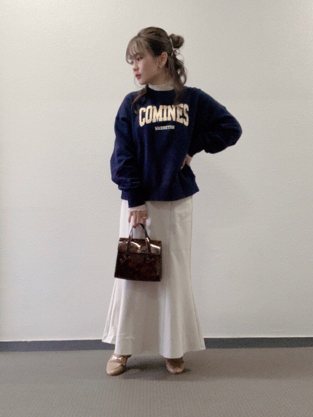 ブルー系のスウェット、ブラウン系のハンドバッグ、ホワイト系のスカートを着用したレディースの春コーディネートの2枚目の写真